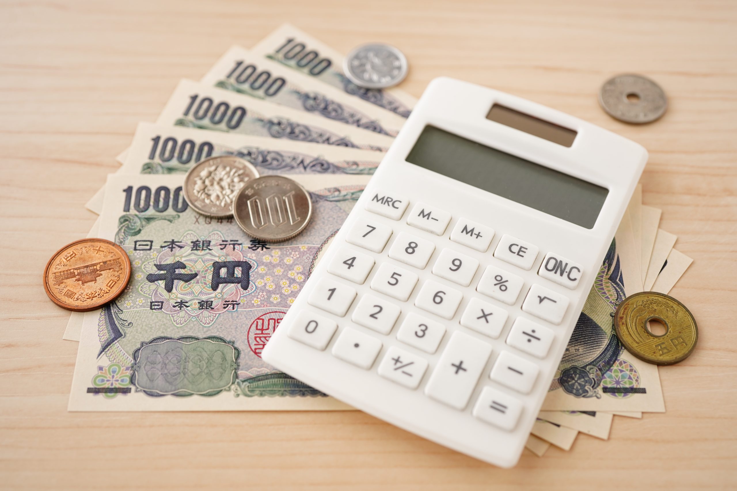 現金と電卓で勘定科目を管理するイメージ